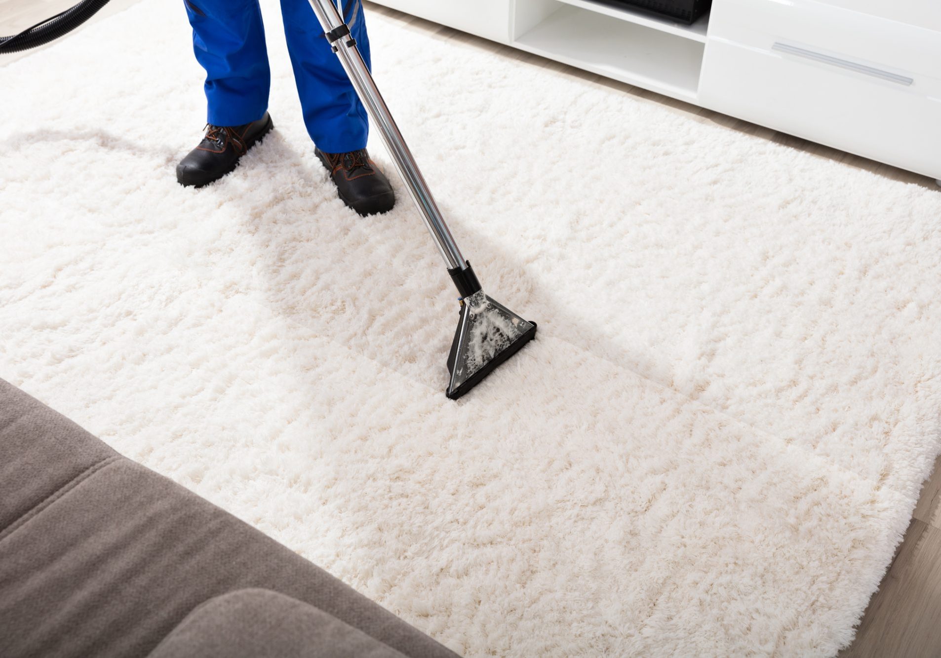 Close-up Of A Janitor Cleaning Carpet With Vacuum Cleaner At Home