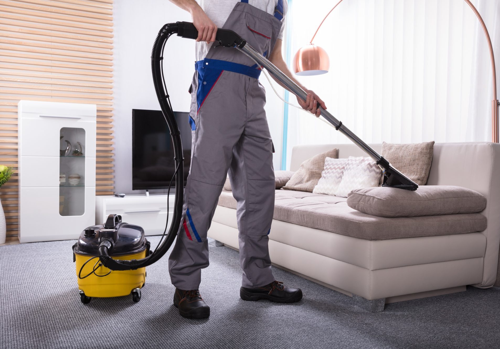 Man Cleaning Sofa In The ving Room Using Vacuum Cleaner At Home