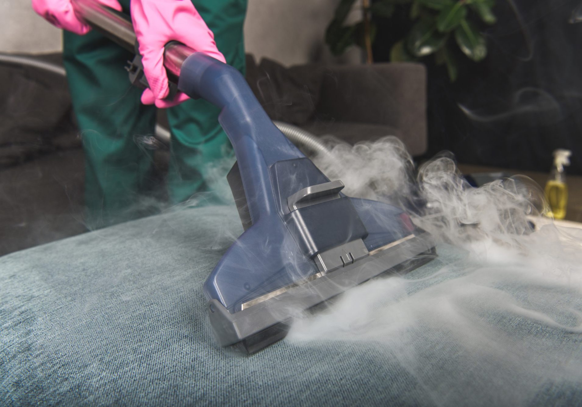cropped shot of person cleaning sofa with vacuum cleaner hot steam cleaning concept